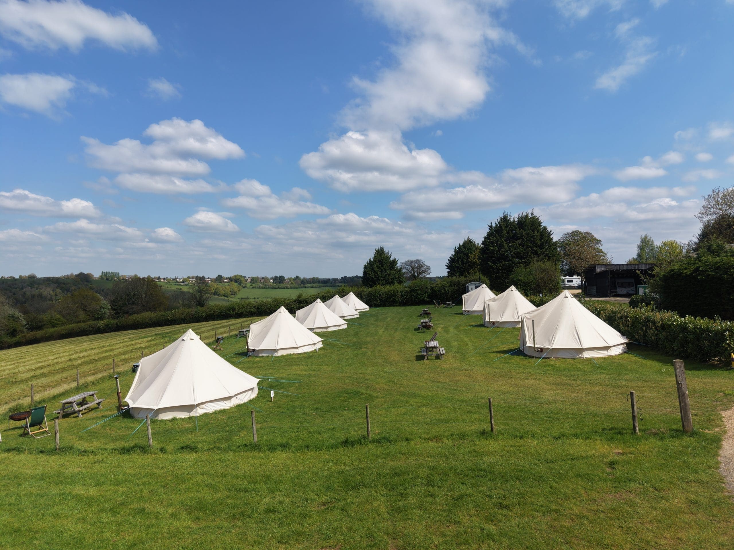 full campsite overview with eight glamping tents and view of the countryside