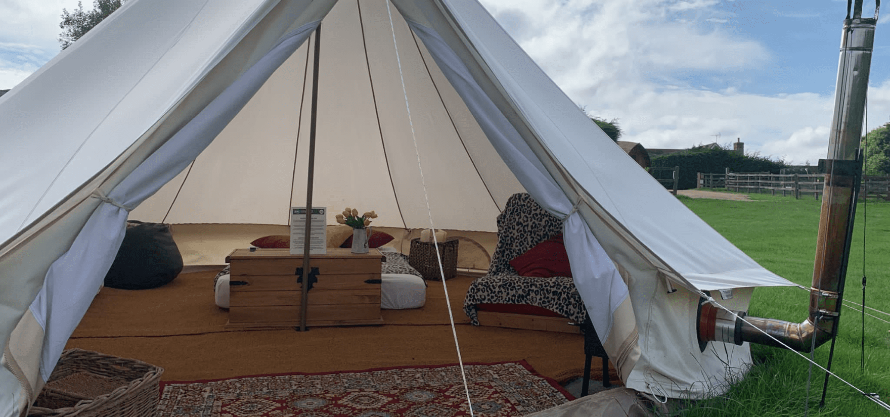 image from outside glamping tent looking inside showing a wooden trunk, chair, and bed