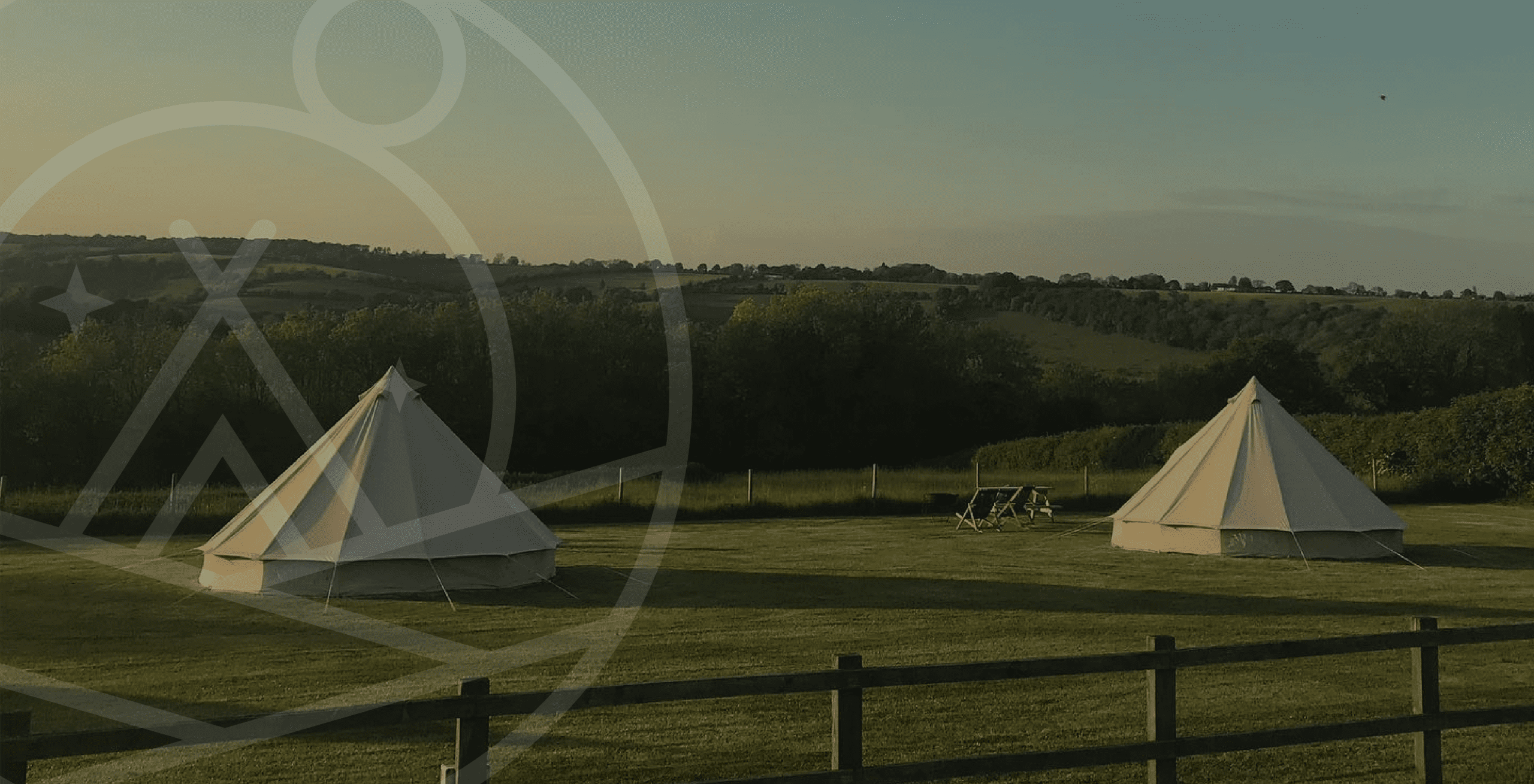 Rolling hills with glamping tents at sunset