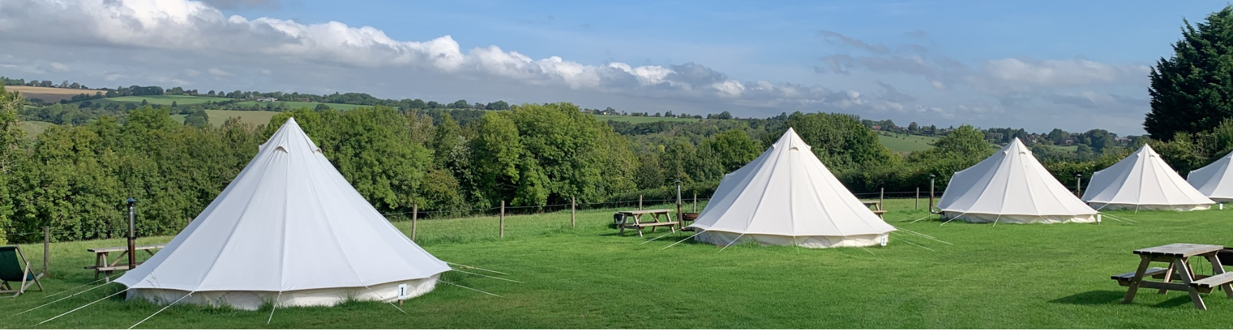overview of glamping tents on a campsite with a view of the countryside behind