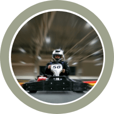 Go-kart racer wearing a white helmet with the number 50 driving on a track.