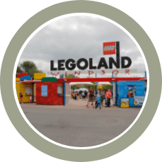 Legoland entrance with a large LEGOLAND sign, colorful gates, and visitors walking through.