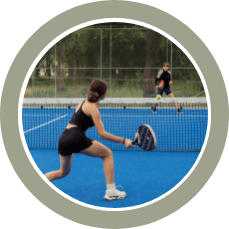 Two people playing padel on a blue court, the person in the foreground is swinging to return the ball