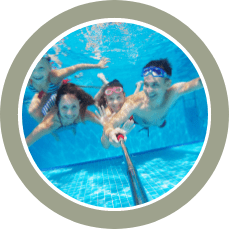 Four people underwater in a swimming pool posing for a selfie.