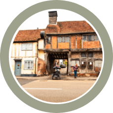 Timber-framed storefront on a quaint street with a cyclist and pedestrians in front.