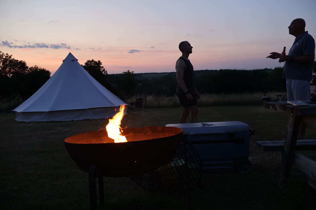 Firepit at dusk with people standing and talking