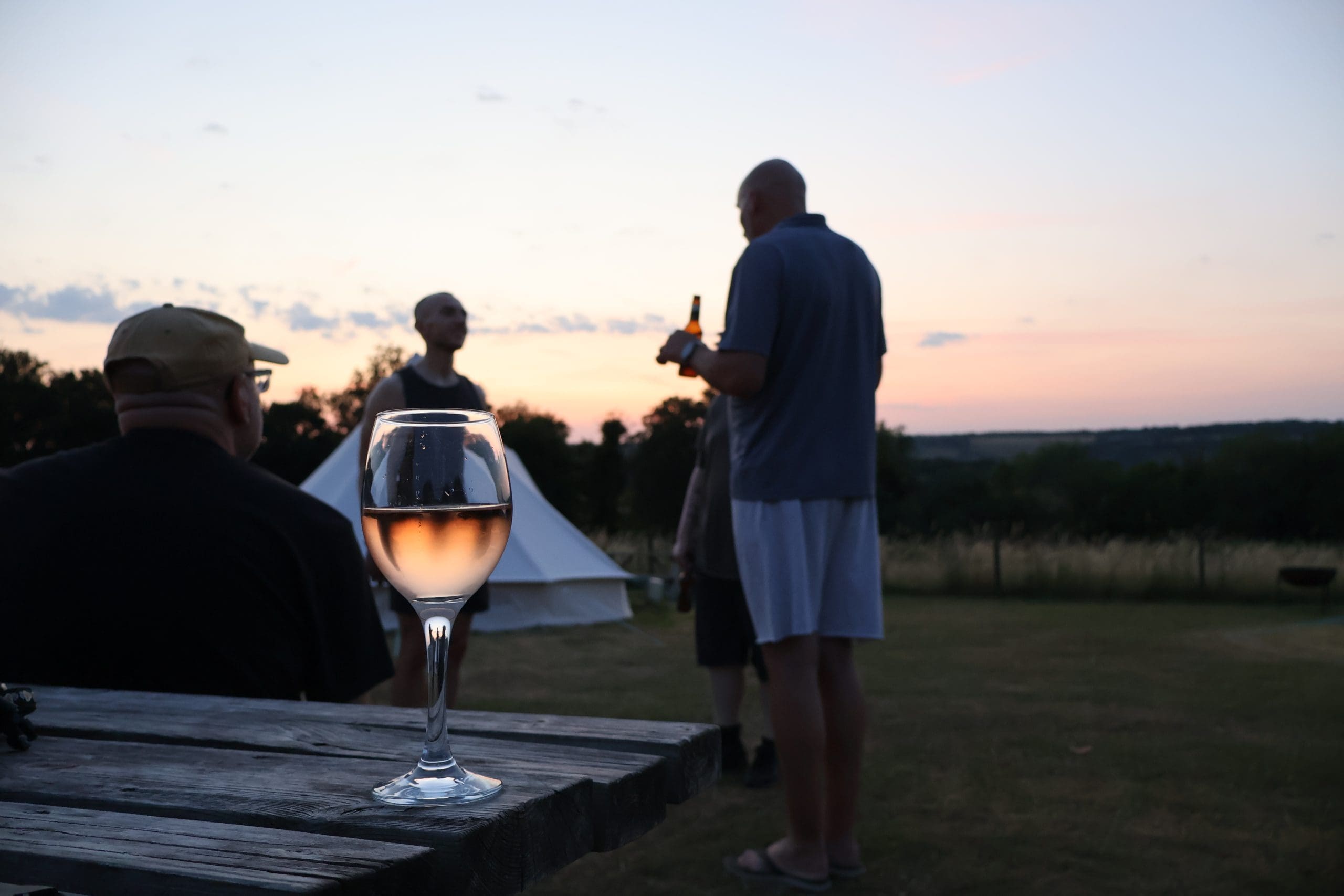 Half full wine glass with people chatting in background